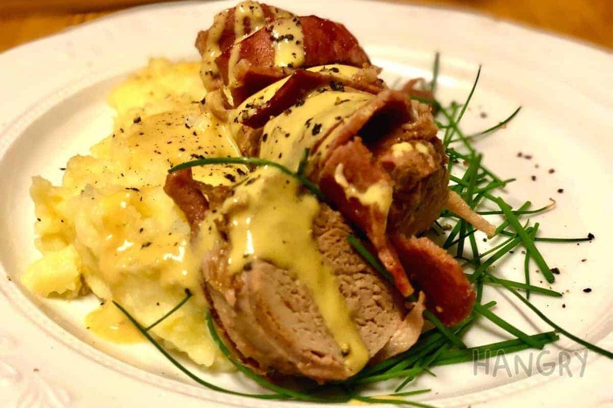 Bacon wrapped pork fillet served on a bed of mustard mash